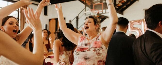 Wedding guests cheering with their hands in the air at an Anchorage, Alaska reception