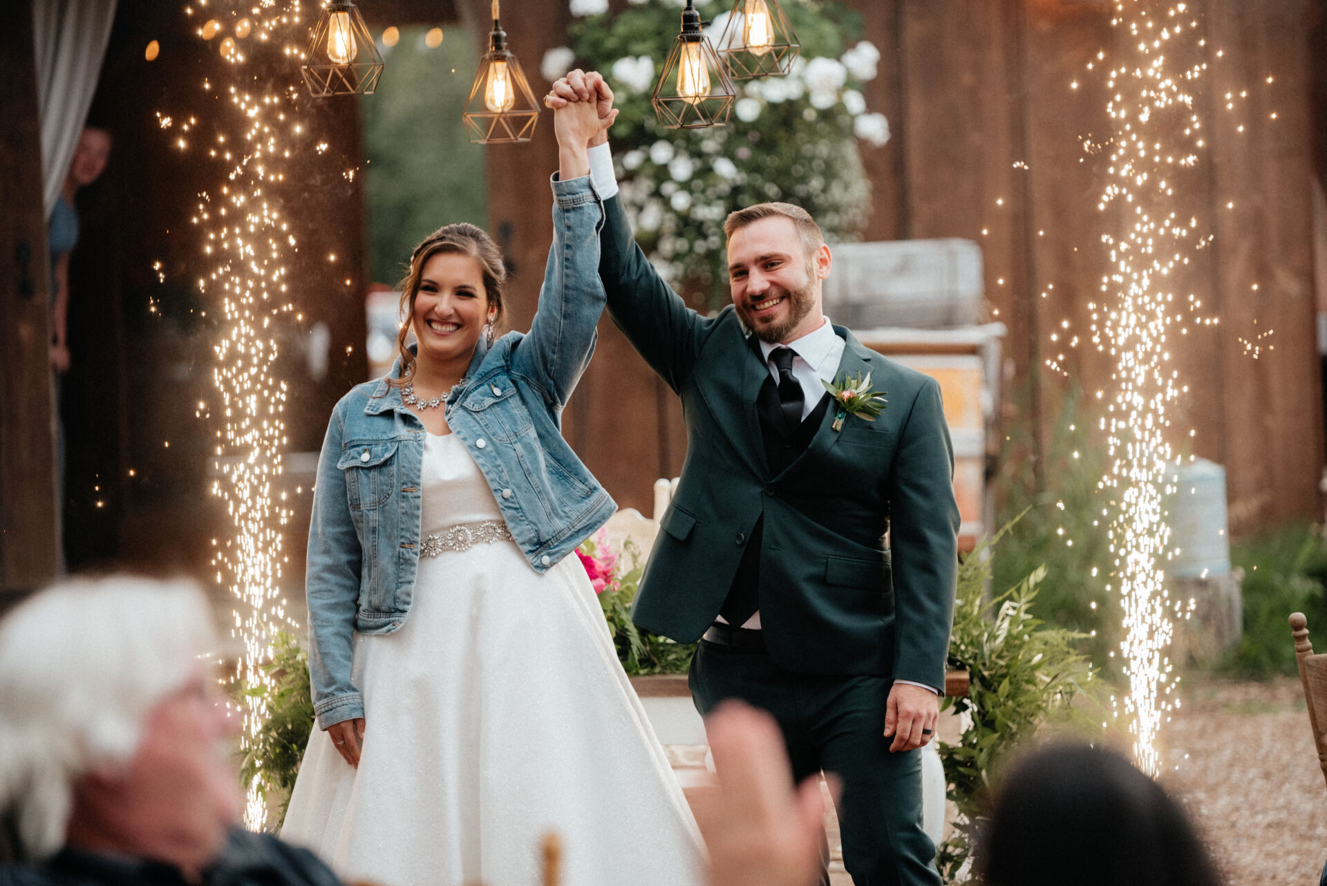 Chalifour Wedding Bride and groom raise their joined hands as cold spark fountains fire behind them at Gloryview Farm in Alaska
